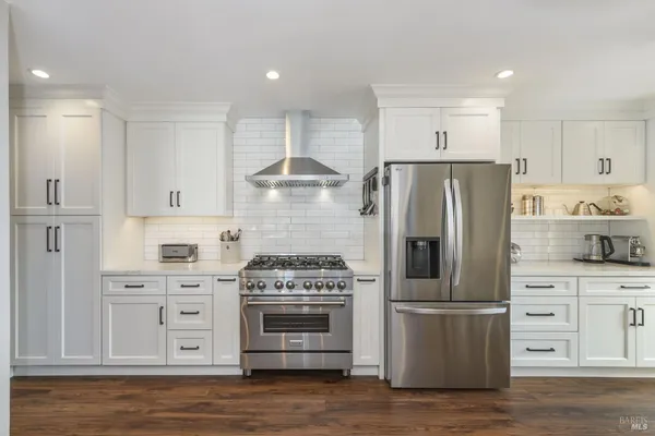 a kitchen with a refrigerator stove and white cabinets
