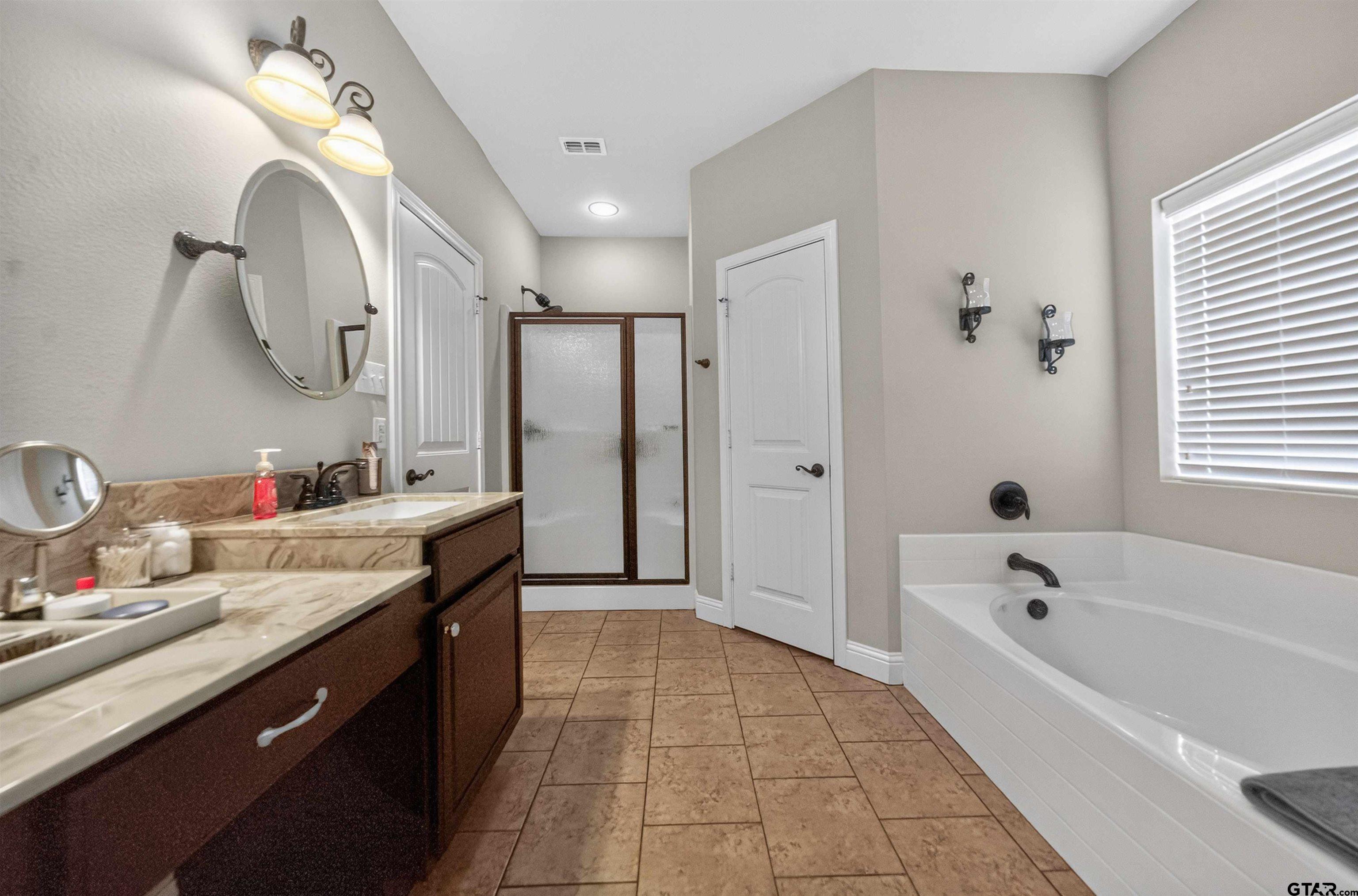 5830 Thompson Place Tyler, TX 75707 - Photo 23 of 35 a spacious bathroom with a tub sink shower and mirror