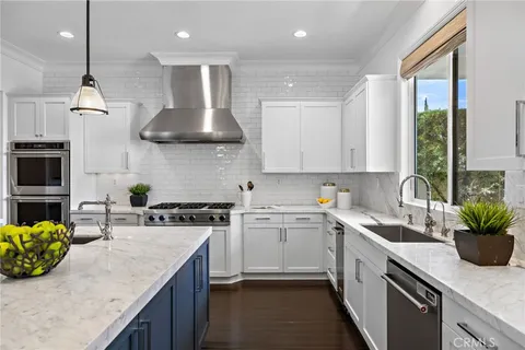 a kitchen with stainless steel appliances granite countertop a refrigerator a sink dishwasher and a wooden cabinets with wooden floor