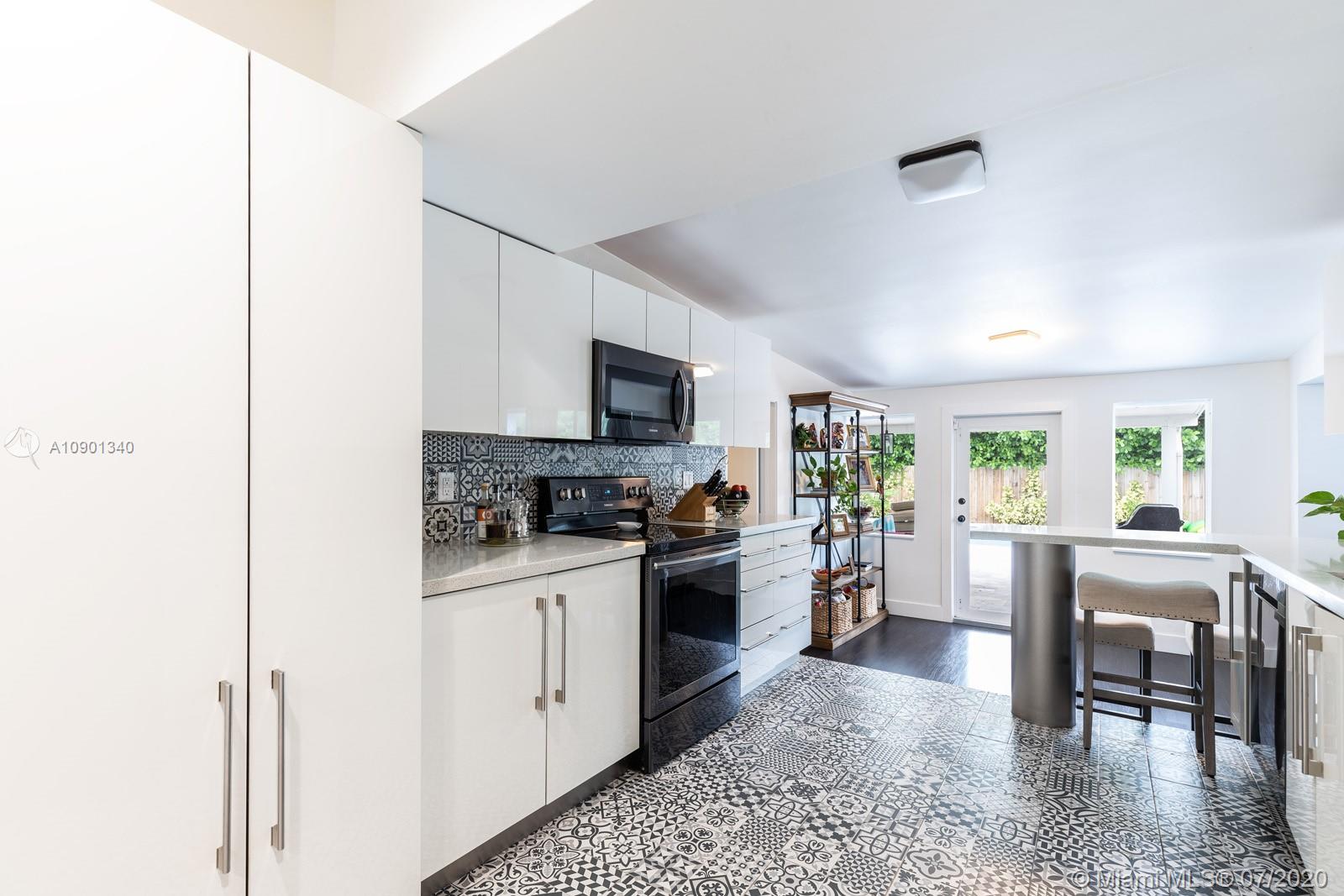 6070 Southwest 25th Street Miami, FL 33155 - Photo 10 of 15 a kitchen with a stove a sink dishwasher a refrigerator and a dining table with wooden floor