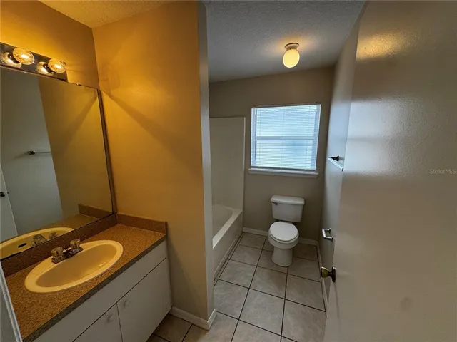 an empty room with a chandelier fan and windows