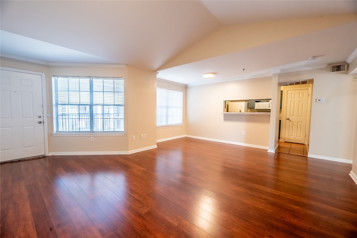 501 West 26th Street, Unit 323 Austin, TX 78705 - Photo 3 of 12 Unfurnished living room with dark wood-style floors, lofted ceiling, and crown molding