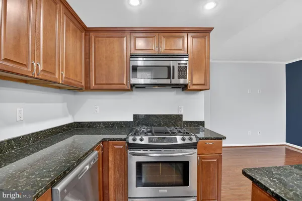 a kitchen with granite countertop a stove top oven microwave and cabinets