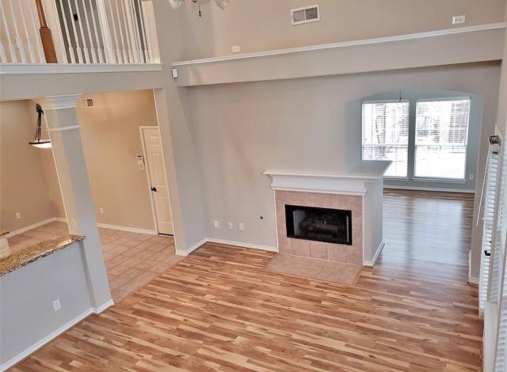 211 Moss Hill Road Irving, TX 75063 - Photo 9 of 14 Unfurnished living room featuring a tile fireplace, light wood-style flooring, and a high ceiling
