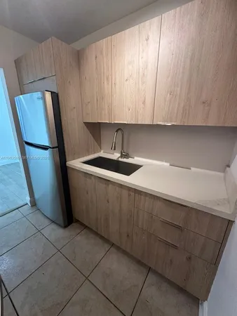 a kitchen with a sink a refrigerator and cabinets