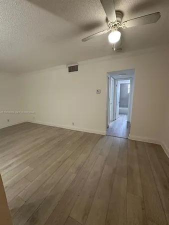 an empty room with wooden floor fan and windows