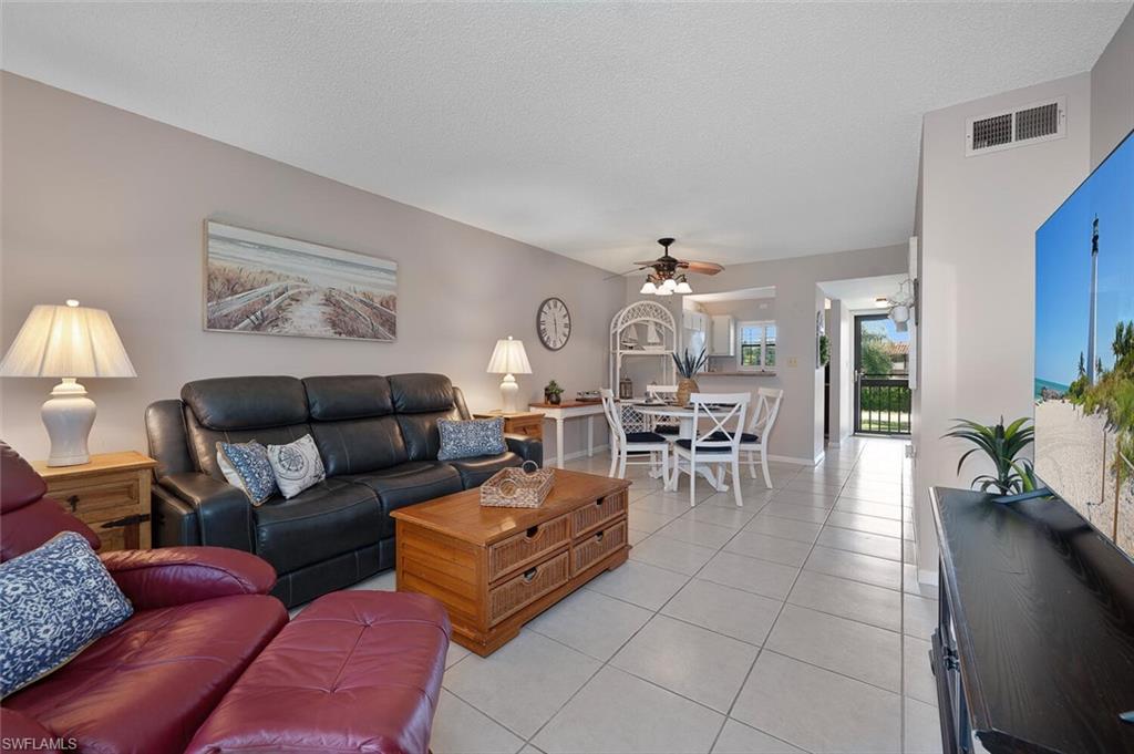 4258 27th Court Southwest, Unit 203 Naples, FL 34116 - Photo 3 of 15 Tiled living room with a textured ceiling and ceiling fan