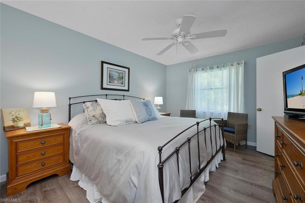 4258 27th Court Southwest, Unit 203 Naples, FL 34116 - Photo 7 of 15 Bedroom with ceiling fan, a textured ceiling, and light hardwood / wood-style flooring