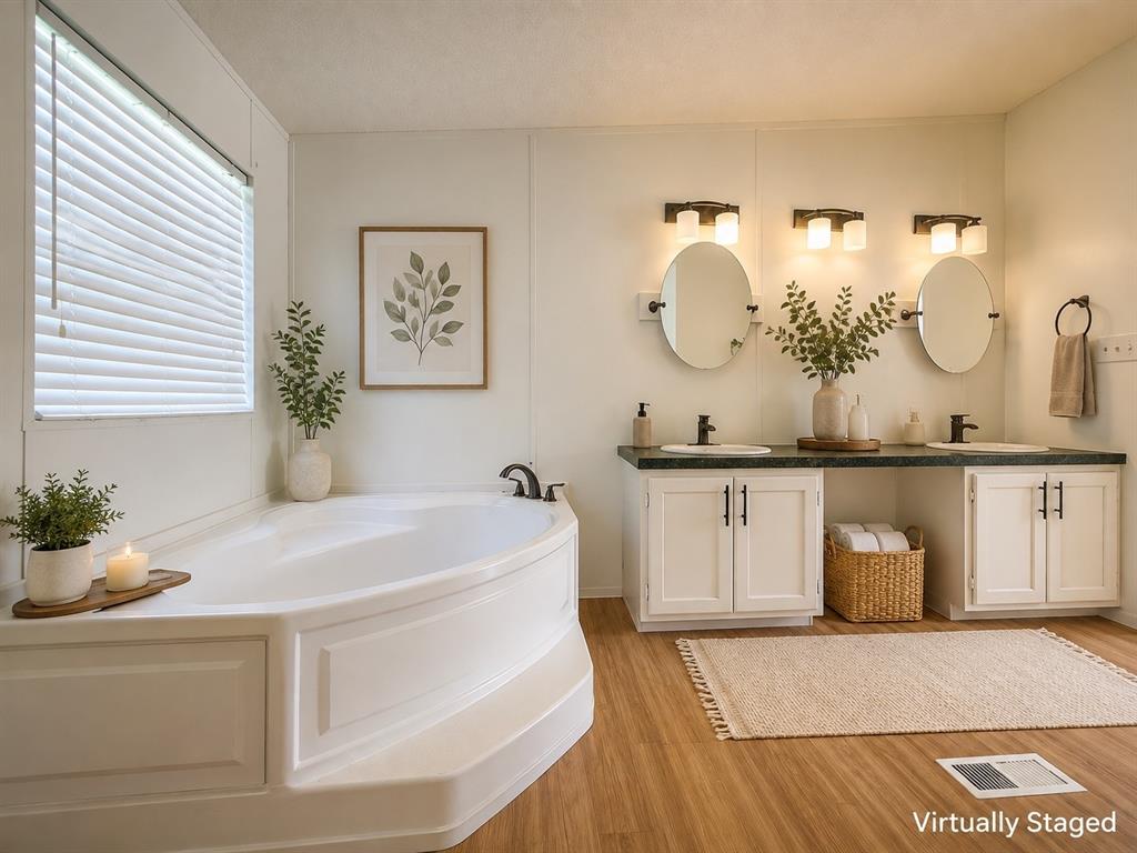 18327 Gholson Road Waco, TX 76705 - Photo 11 of 19 Corner soaking tub with a window, dual vanity with undermount sinks, and wood-finish flooring