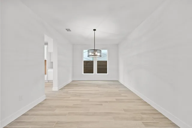 a view of an empty room with window and wooden floor