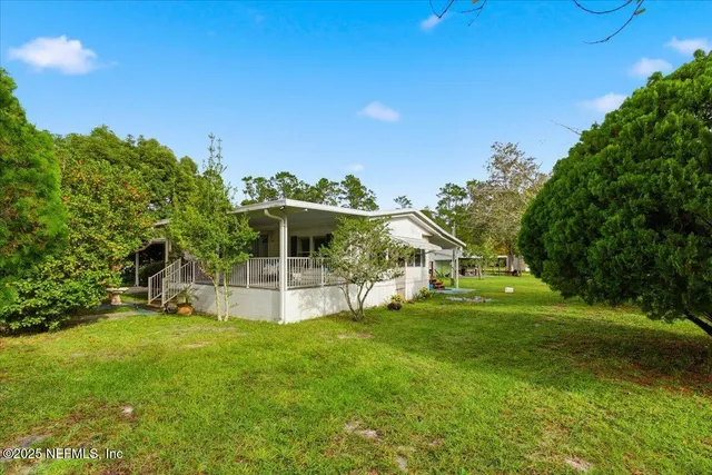 a view of a house with a big yard and large trees