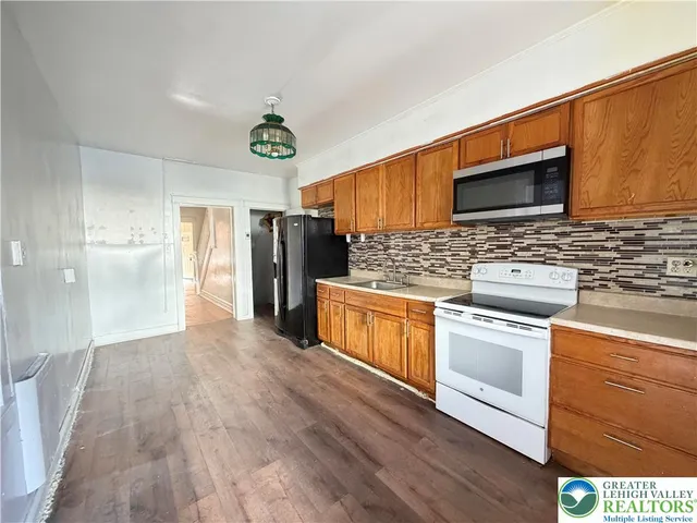 a kitchen with stainless steel appliances granite countertop a refrigerator a stove top oven a sink and dishwasher