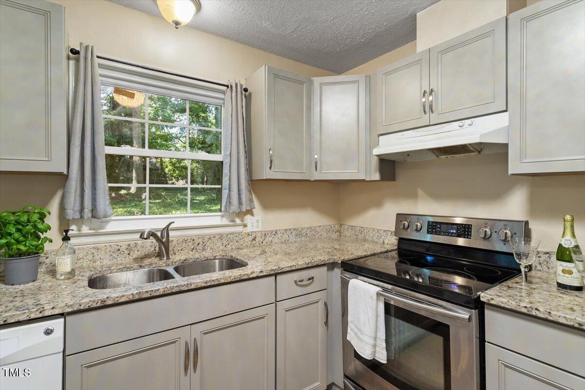 5309 Covey Court Raleigh, NC 27609 - Photo 22 of 47 a kitchen with granite countertop a sink stainless steel appliances white cabinets and a window