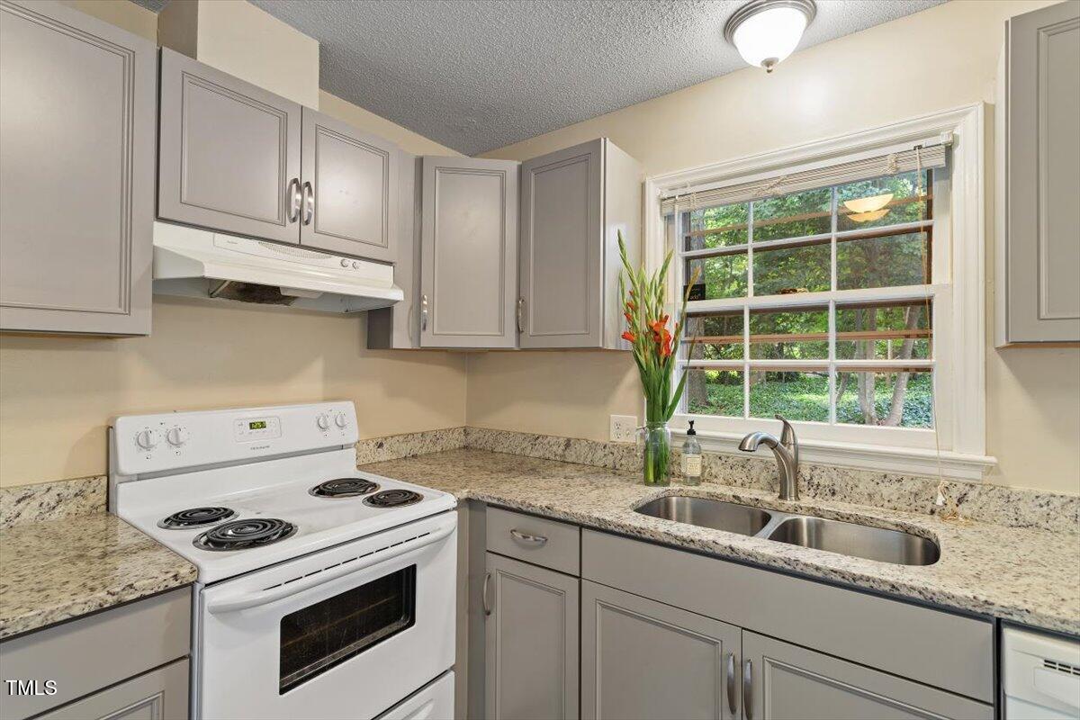 5309 Covey Court Raleigh, NC 27609 - Photo 37 of 47 a kitchen with granite countertop white cabinets and white appliances