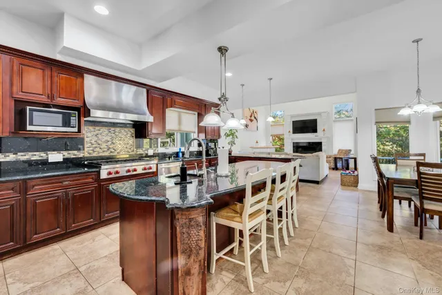 a kitchen with stainless steel appliances granite countertop a stove top oven a sink dishwasher a dining table and chairs with wooden floor