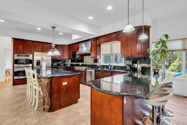 a kitchen with stainless steel appliances granite countertop a stove top oven a sink dishwasher a dining table and chairs with wooden floor