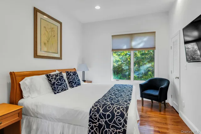 a large bed sitting in a bedroom next to a window with chair and a large window