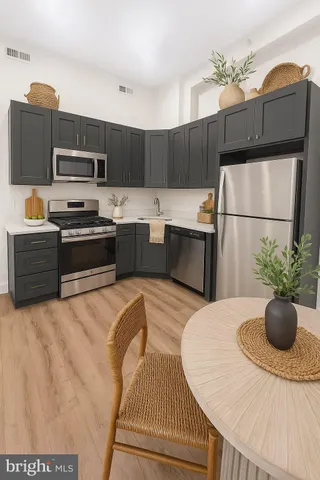 a kitchen with stainless steel appliances kitchen island granite countertop a refrigerator a stove top oven a sink with dining table and chairs