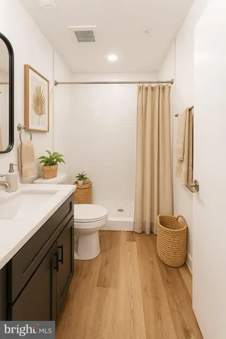 a bathroom with a granite countertop sink a toilet a mirror and shower