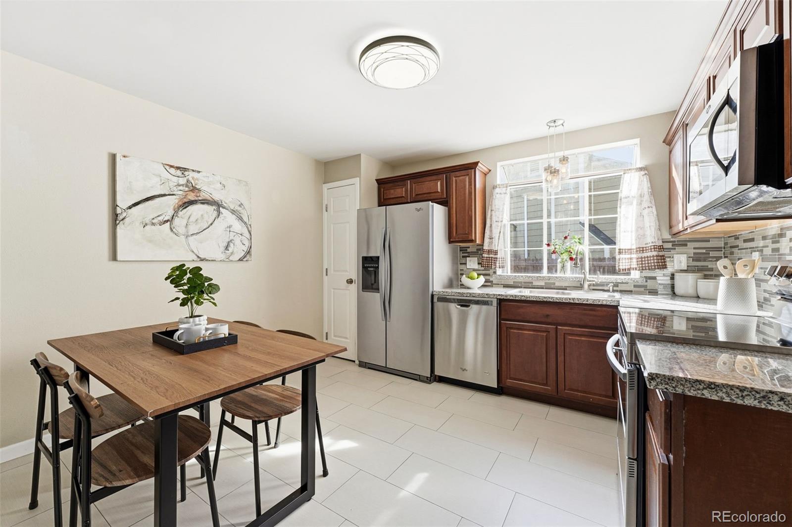 17660 Snowberry Way Parker, CO 80134 - Photo 15 of 38 a kitchen with granite countertop a table chairs a refrigerator and wooden cabinets