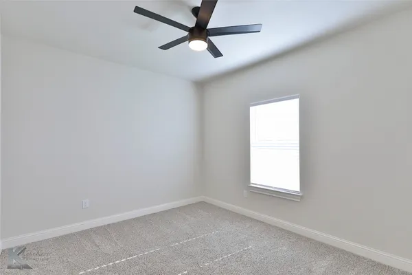 an empty room with a window and a fan