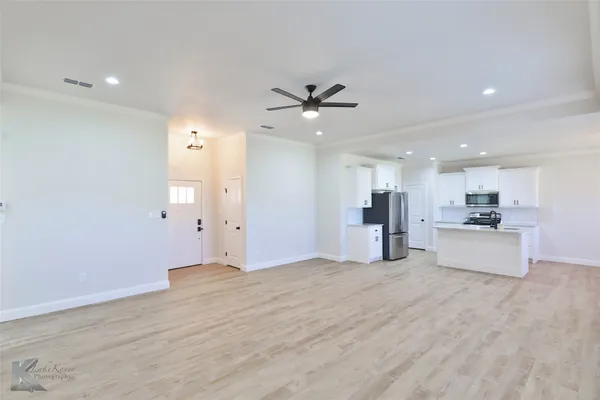 a view of a big room with wooden floor and a kitchen
