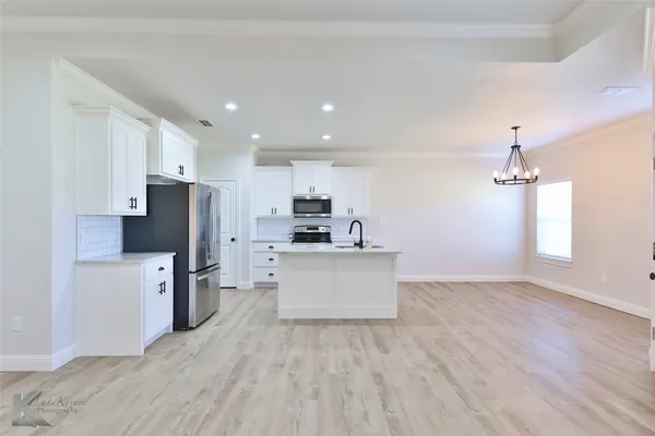 a view of kitchen with stainless steel appliances refrigerator stove microwave and cabinets