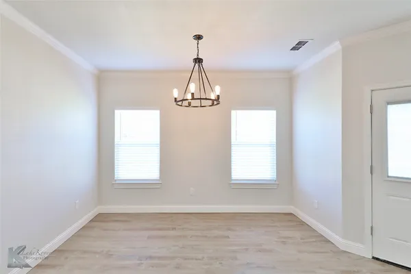 an empty room that has a window and wooden floor