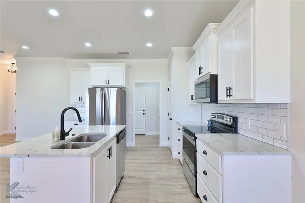 a kitchen with kitchen island stainless steel appliances a sink stove and refrigerator