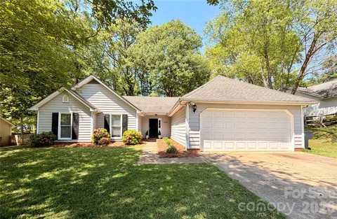 a front view of house with yard and trees in the background
