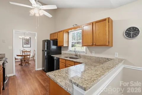 a kitchen with stainless steel appliances granite countertop a sink dishwasher stove and refrigerator with wooden floor