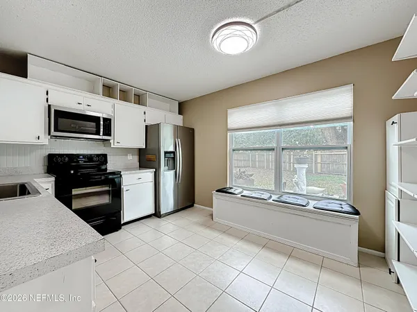 an empty room with wooden floor a ceiling fan and windows