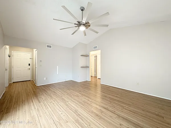 an empty room with wooden floor and windows