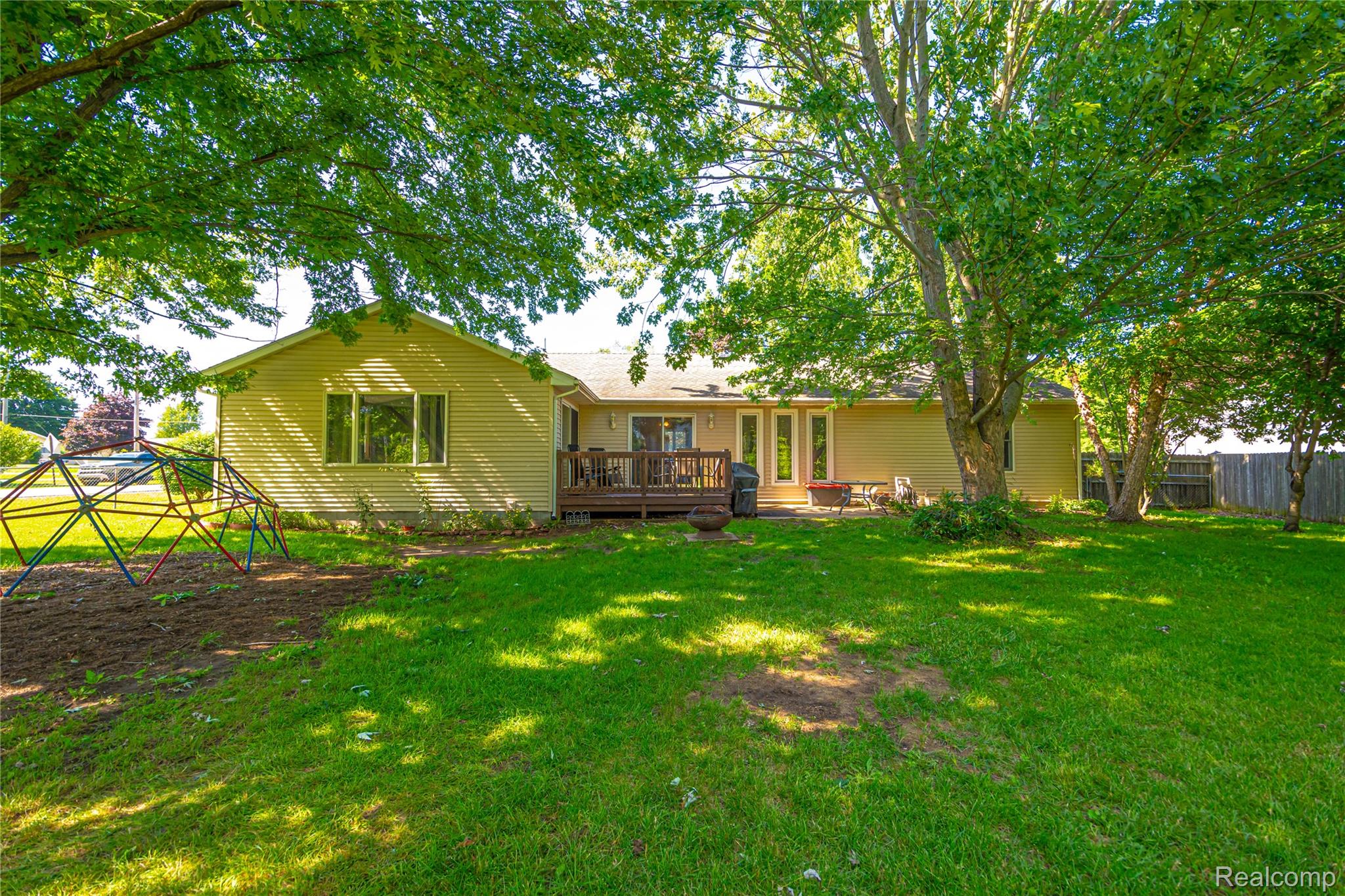 3241 Simpson Road Fort Gratiot, MI 48059 - Photo 6 of 27 Expansive backyard featuring a manicured lawn, mature trees, and a wooden deck