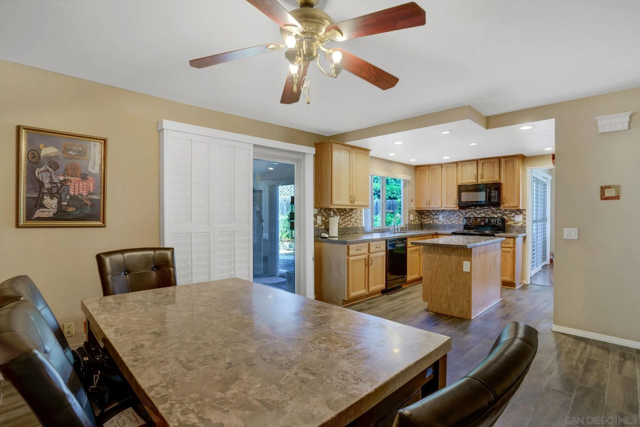 3006 Gayla Court Spring Valley, CA 91978 - Photo 12 of 39 a kitchen with stainless steel appliances granite countertop a stove top oven a sink a dining table and chairs with wooden floor