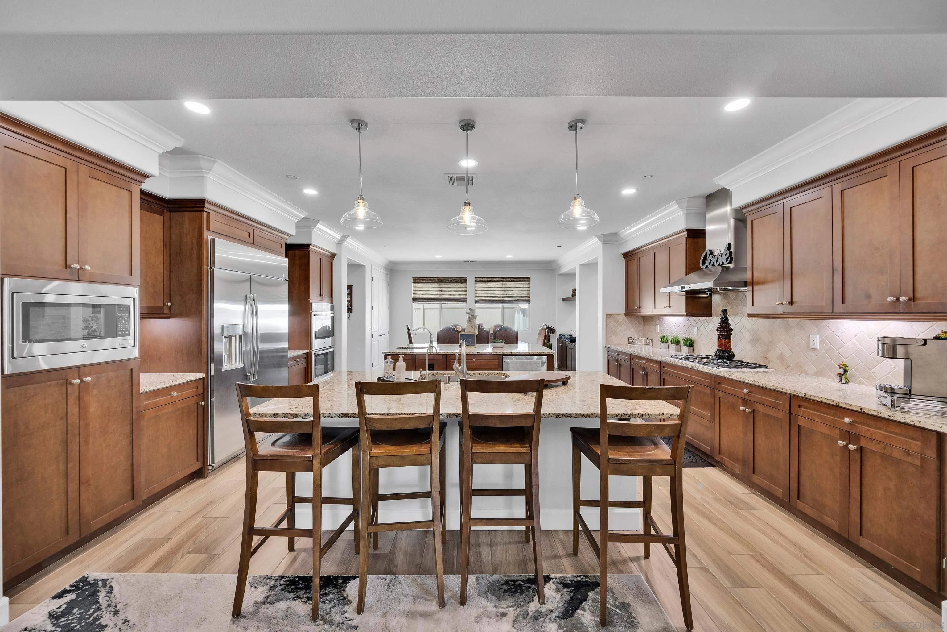 5620 Rancho Del Caballo Bonsall, CA 92003 - Photo 17 of 62 a kitchen with stainless steel appliances kitchen island granite countertop a dining table chairs and white cabinets