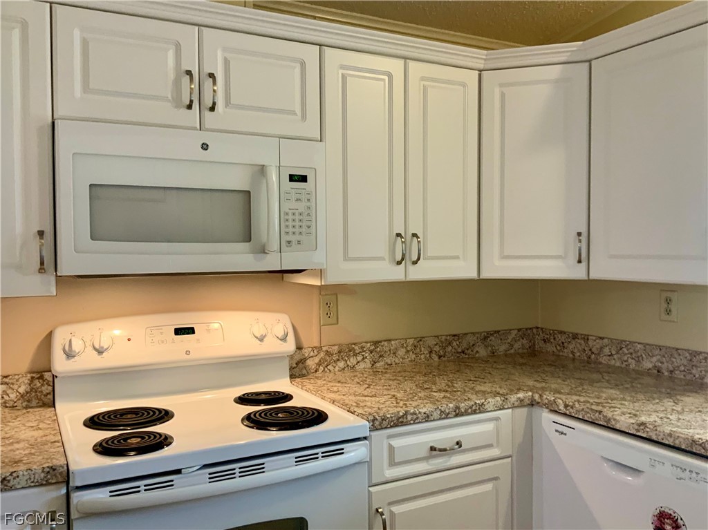 15550 Burnt Store Road, Unit 89 Punta Gorda, FL 33955 - Photo 6 of 28 a kitchen with granite countertop cabinets and white appliances