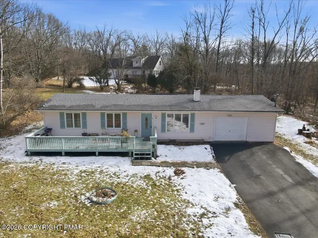a front view of a house with a yard covered with snow and trees