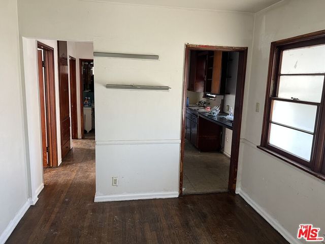 a view of a refrigerator in kitchen and an empty room with wooden floor windows