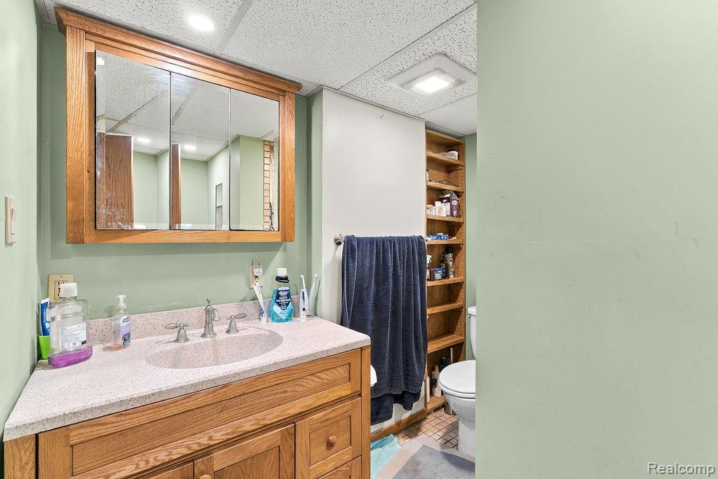 87 Burley Road Columbiaville, MI 48421 - Photo 26 of 31 Corner vanity with wood-finish cabinetry, integrated sink, and light-toned countertop
