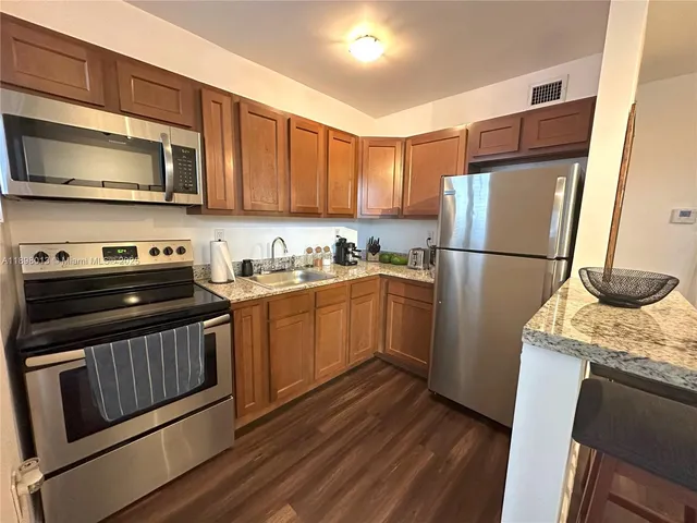 a kitchen with a sink a microwave a refrigerator and cabinets