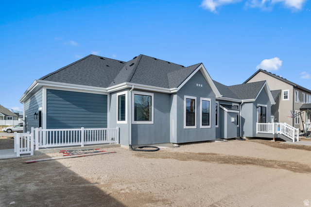 11673 South Halls Crk Road Draper, UT 84020 - Photo 5 of 22 Modern exterior featuring a combination of blue siding and stucco finishes, dark shingle roofing, white window trim, and a white picket fence enclosing a patio area