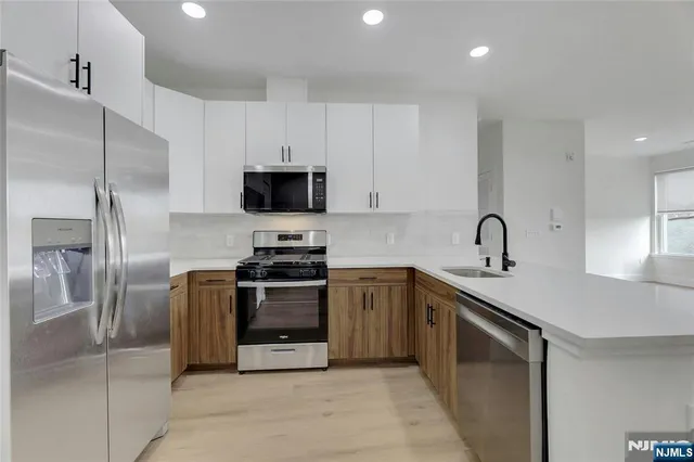 a kitchen with stainless steel appliances granite countertop a sink a stove a refrigerator and a refrigerator