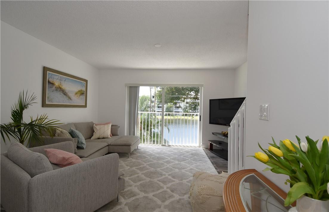217 Riviera Circle, Unit 217 Weston, FL 33326 - Photo 12 of 58 a living room with furniture a flat screen tv and a floor to ceiling window