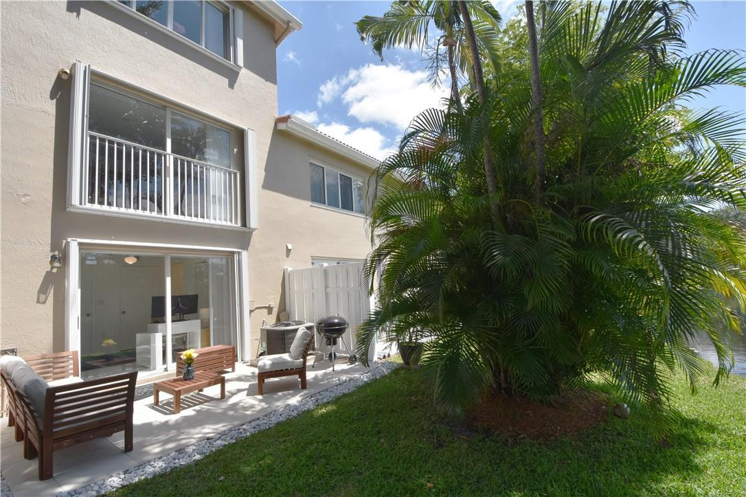 217 Riviera Circle, Unit 217 Weston, FL 33326 - Photo 48 of 58 a view of a patio with table and chairs and potted plants and large tree