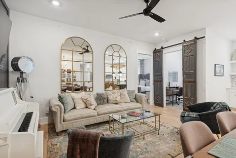 a living room with furniture a chandelier fan and a large window