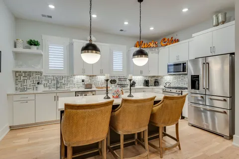 a kitchen with stainless steel appliances granite countertop a sink a stove a refrigerator and island with wooden floor