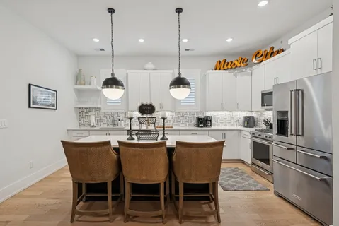 a kitchen with stainless steel appliances granite countertop a sink dishwasher a stove and a microwave oven with white cabinets