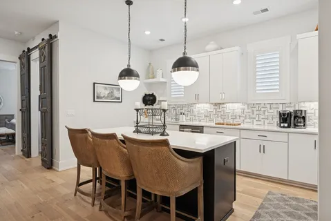 a kitchen with stainless steel appliances granite countertop a sink a stove a dining table and chairs