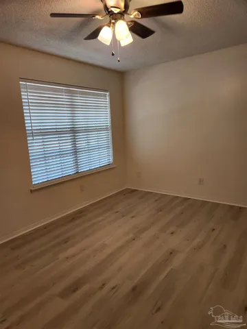 an empty room with wooden floor fan and windows